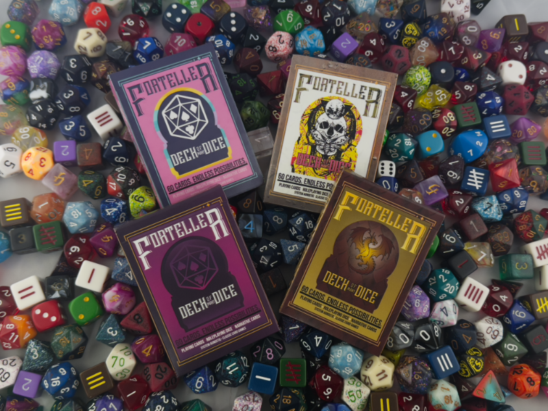 Deck of Many Dice packs laying on top of a huge pool of assorted gaming dice.